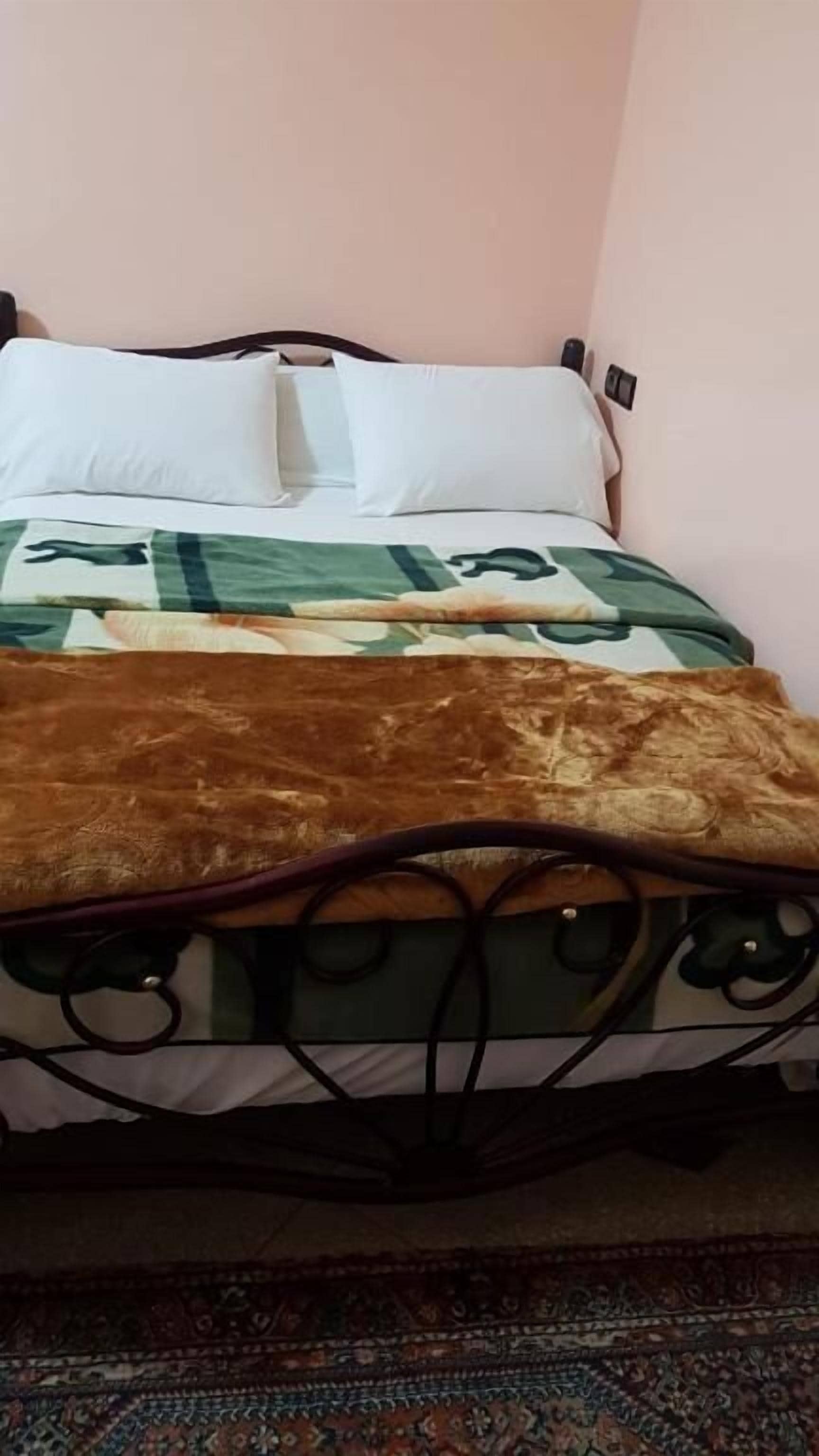 A bed with a patterned bedspread, pillows, and a headboard.