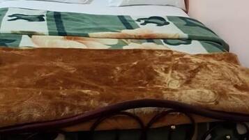 A bed with a patterned bedspread, pillows, and a headboard.