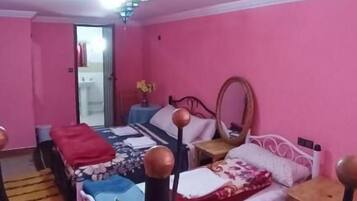 Ein zart rosa gestaltetes Schlafzimmer mit Bett, Nachttisch und Spiegel.