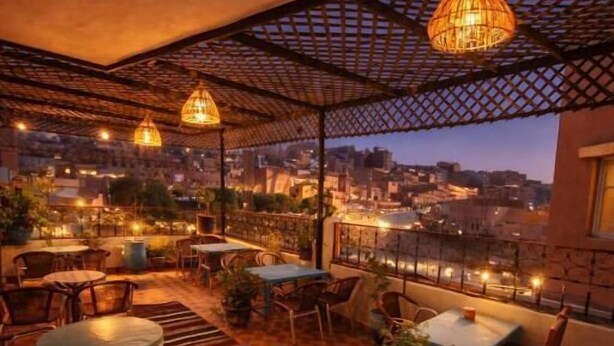 An outdoor terrace with tables and chairs, a checkered floor, and hanging lights.