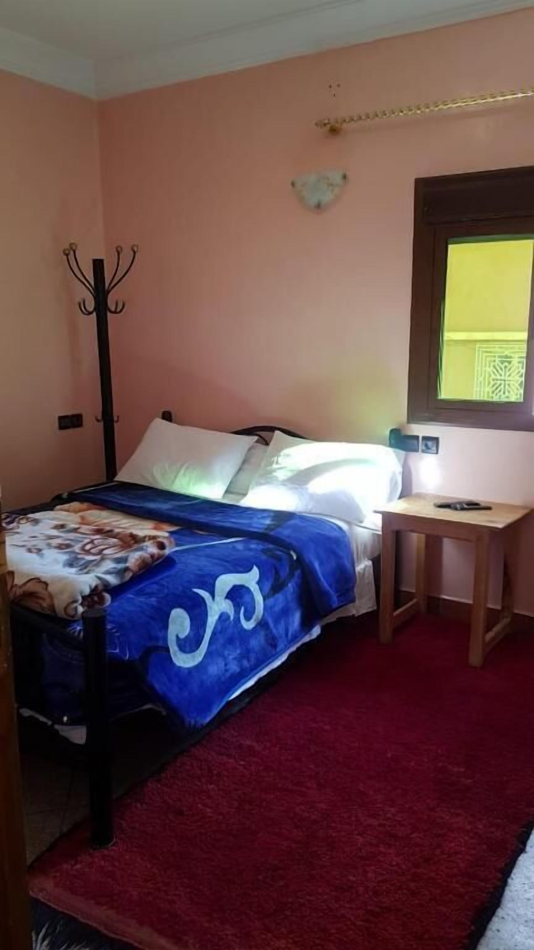 A bedroom with a bed, a desk, a chair, and a window.