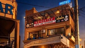 A hotel with a restaurant on the ground floor, outdoor seating, and a sign indicating a hotel.