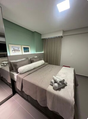 Ein modernes Hotelzimmer mit einem großen Bett, einem Flachbildfernseher und zwei gerahmten Bildern an der Wand.