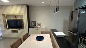 Moderni keittiö, jossa on ruokapöytä, tuolit, jääkaappi ja sisäänrakennettu uuni.