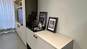 Moderni olohuone, jossa on valkoinen mediakeskus, suuri ikkuna läpikuultavilla verhoilla ja laatoitettu lattia.
