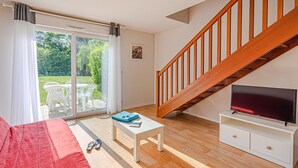 A living room with a sofa, a coffee table, a TV, and a staircase. - Comfortable House Stay for 6 in Plescop (Plescop)