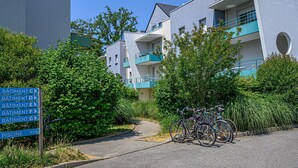 A residential building with multiple balconies, a sign indicating directions to various apartments and a swimming pool, and bicycles parked in front. - Comfortable House Stay for 6 in Plescop (Plescop)