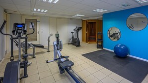 A gym with exercise equipment, a blue wall, and a mirror. - Comfortable House Stay for 6 in Plescop (Plescop)