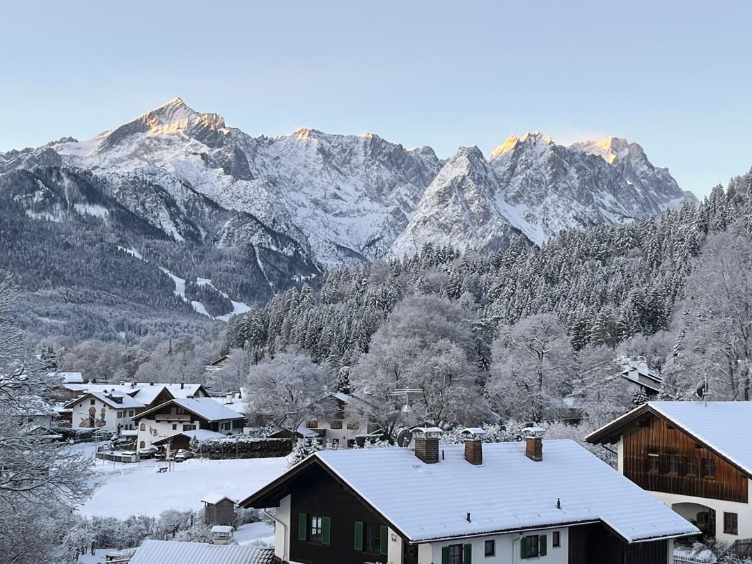 Een bergdorpsgezicht met met sneeuw bedekte huizen en een opvallende bergtop op de achtergrond.