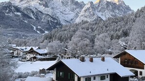 A mountain village with snow-covered houses and a prominent mountain peak in the background. - Alpine Loft Marianne über Garmisch-Partenkirchen (Garmisch-Partenkirchen)