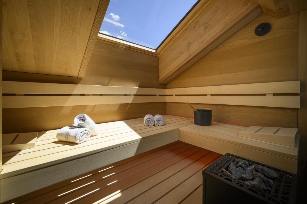 Een sauna met houten banken, een dakraam en handdoeken.