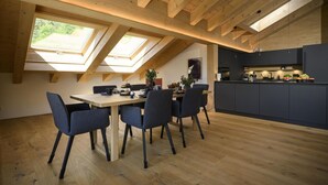 A modern kitchen with skylights, a dining area with a table and chairs, and a view of greenery outside. - Alpine Loft Marianne über Garmisch-Partenkirchen (Garmisch-Partenkirchen)