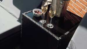 Um pátio com uma mesa, duas cadeiras de descanso, um balde de champanhe e uma garrafa.