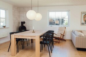 A modern dining area with a wooden table, black chairs, and a white pendant light. - Modern holiday home with spa at Grenaa Beach (Grenaa)