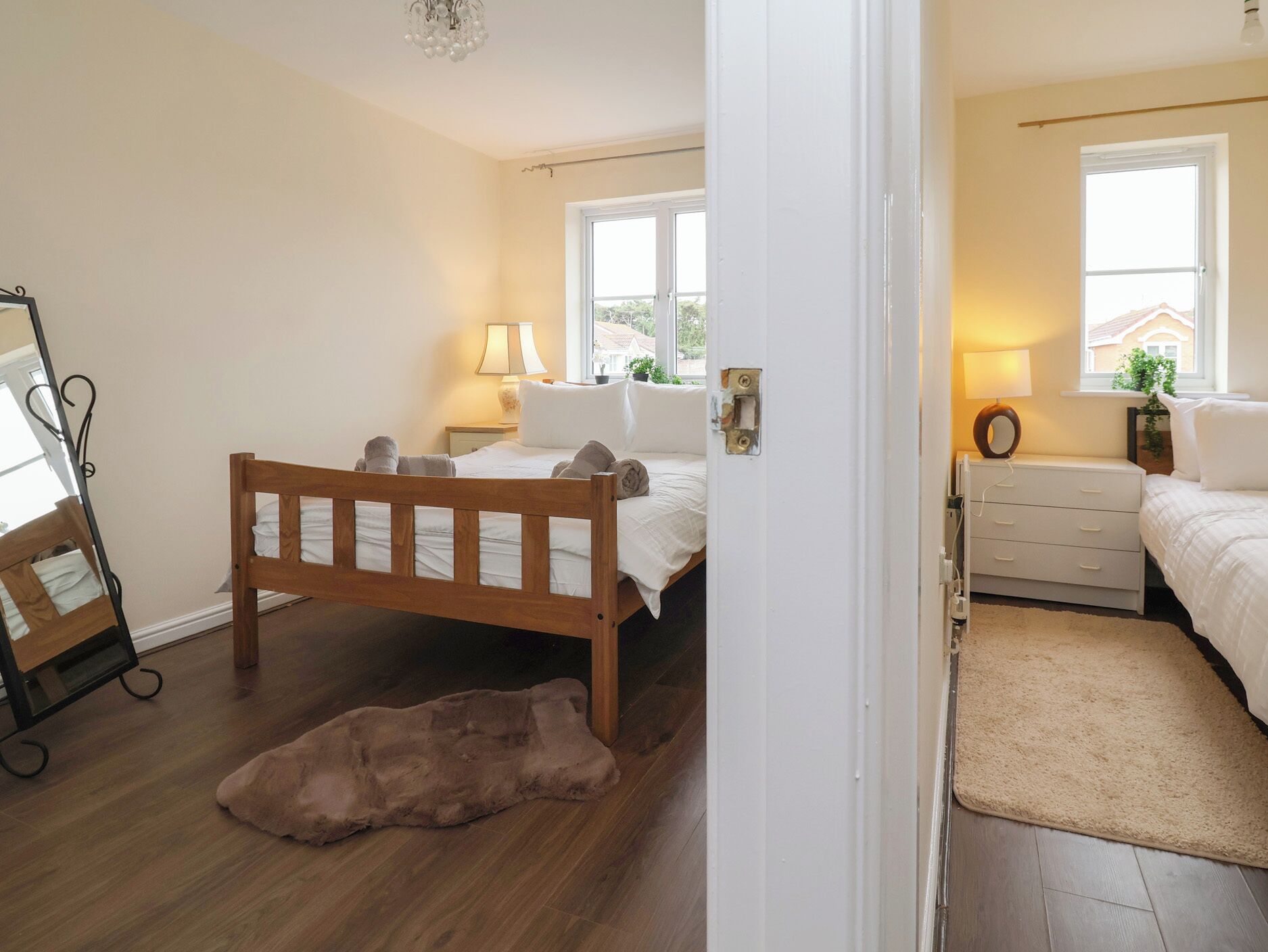 A bedroom with a wooden bed, a nightstand with a lamp, a dresser, and a mirror.