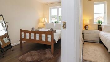 A bedroom with a wooden bed, a nightstand with a lamp, a dresser, and a mirror.