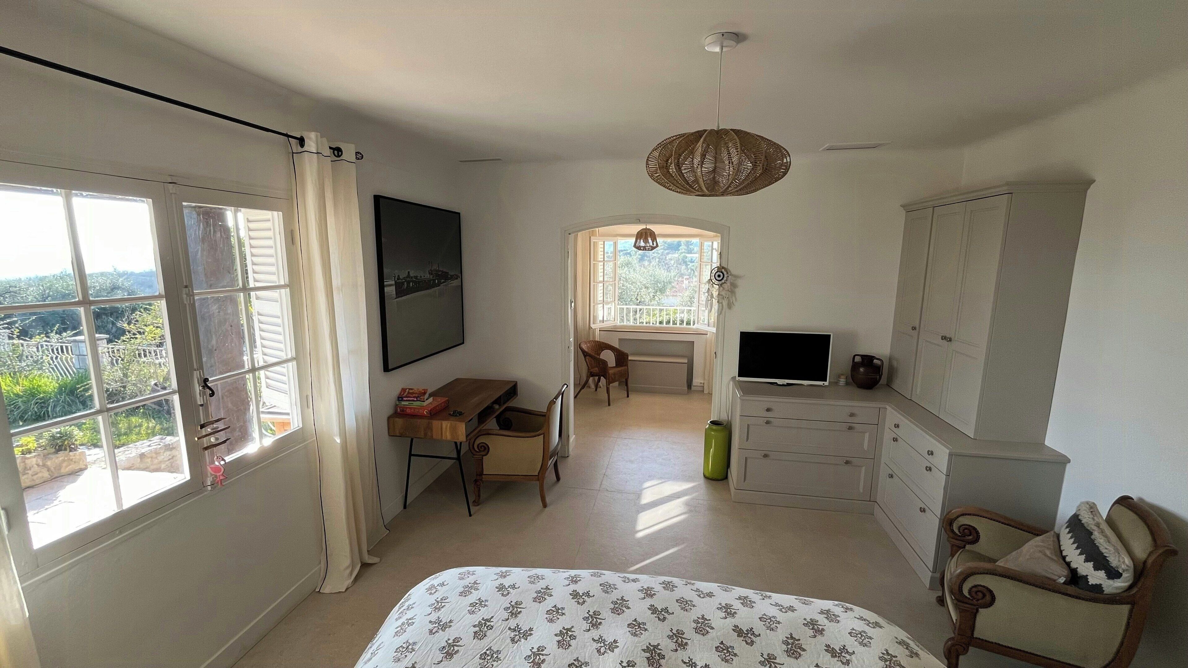 A bedroom with a bed, a desk, a chair, a television, and a wardrobe.