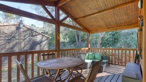 A covered outdoor deck with a round table and chairs, a cushioned seating area, and a wooden railing. - Quiet Detached Chalet for Five (Sollies-Toucas)