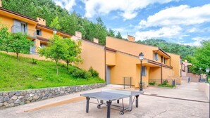 A courtyard with a ping pong table, stone wall, and buildings with balconies. - Peaceful Alpine Triplex Escape (Guillaumes)