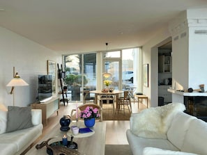 A modern living room with a sofa, coffee table, and a dining area with chairs and a table.