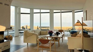 A spacious living area with large windows, a dining table, and modern furniture. - Restored fisherman's house on cliff in Thy (Hanstholm)