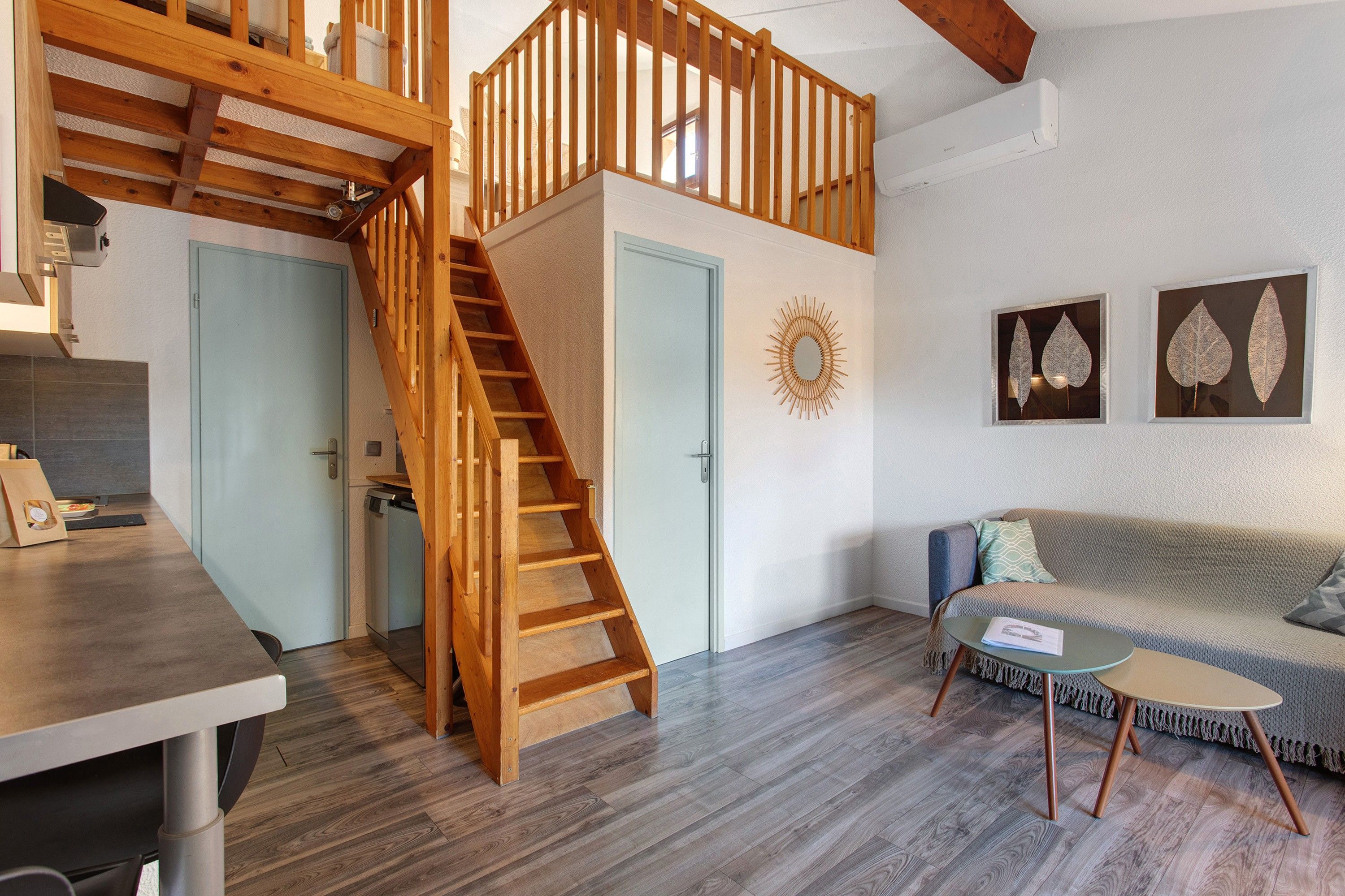 Un intérieur moderne avec un escalier en bois, un canapé, une petite table et un élément décoratif mural.