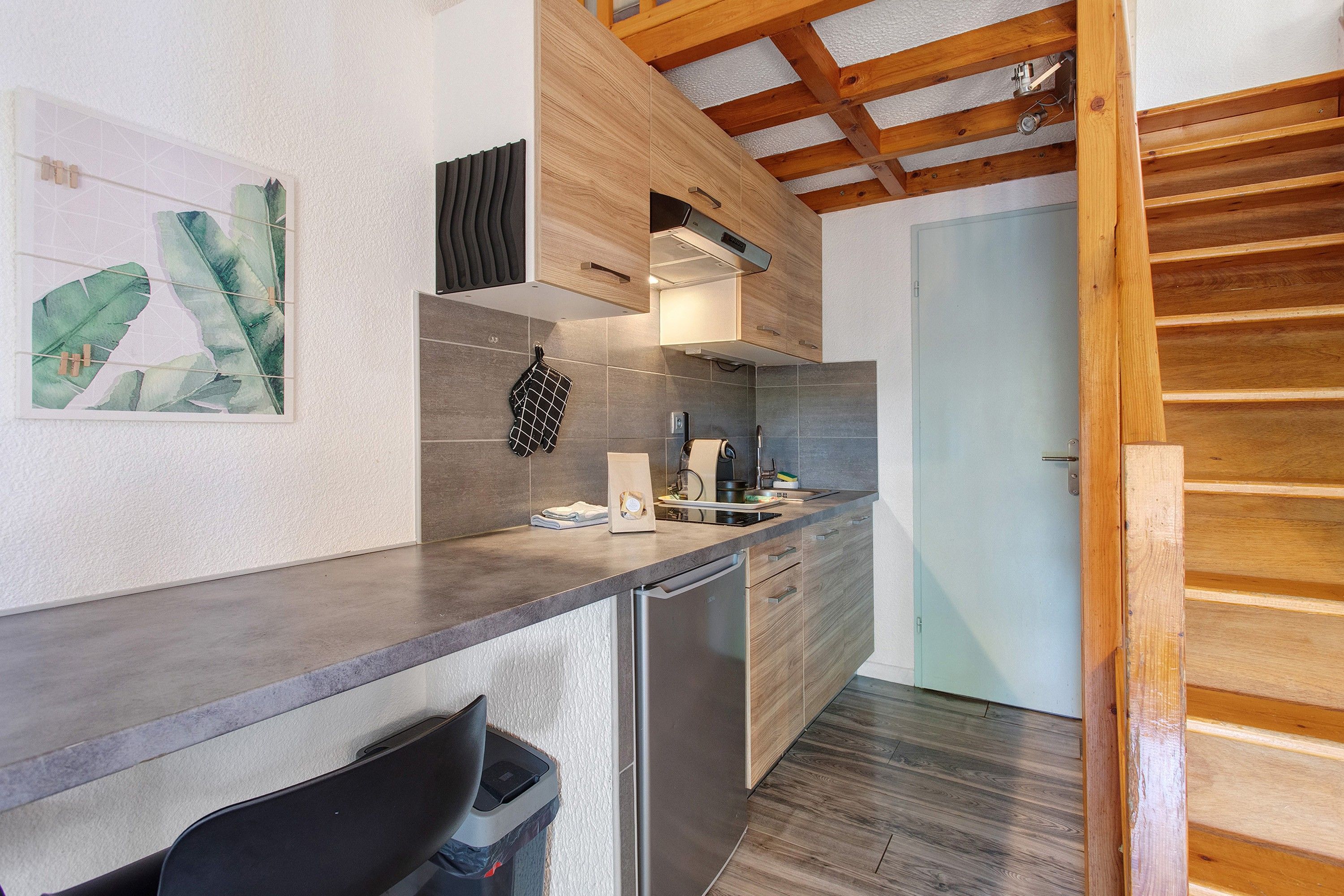 Una cocina moderna con lavavajillas integrado, techo de madera y salpicadero de azulejos.
