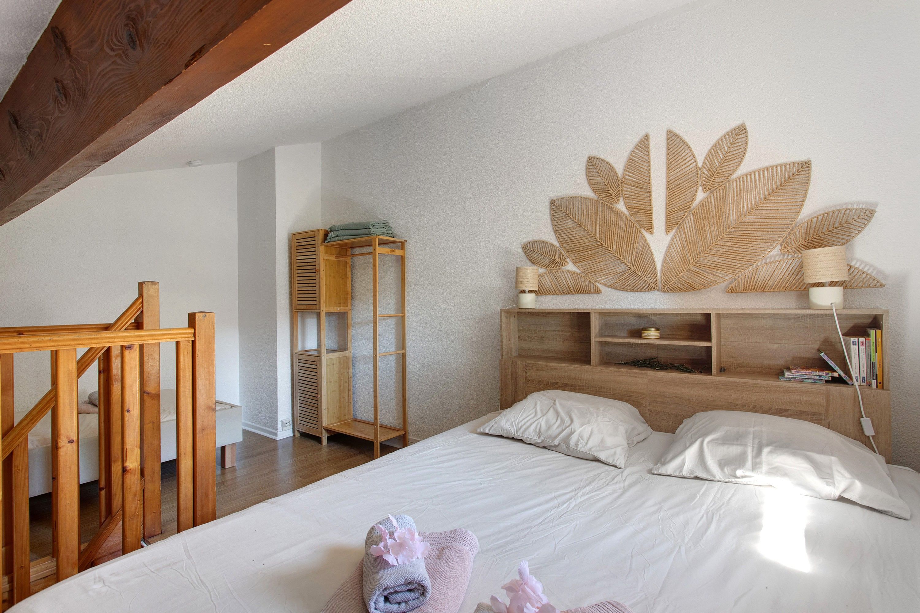 Un dormitorio con estructura de cama de madera, una mesita de noche, un estante montado en la pared y un diseño decorativo con motivos de hojas.