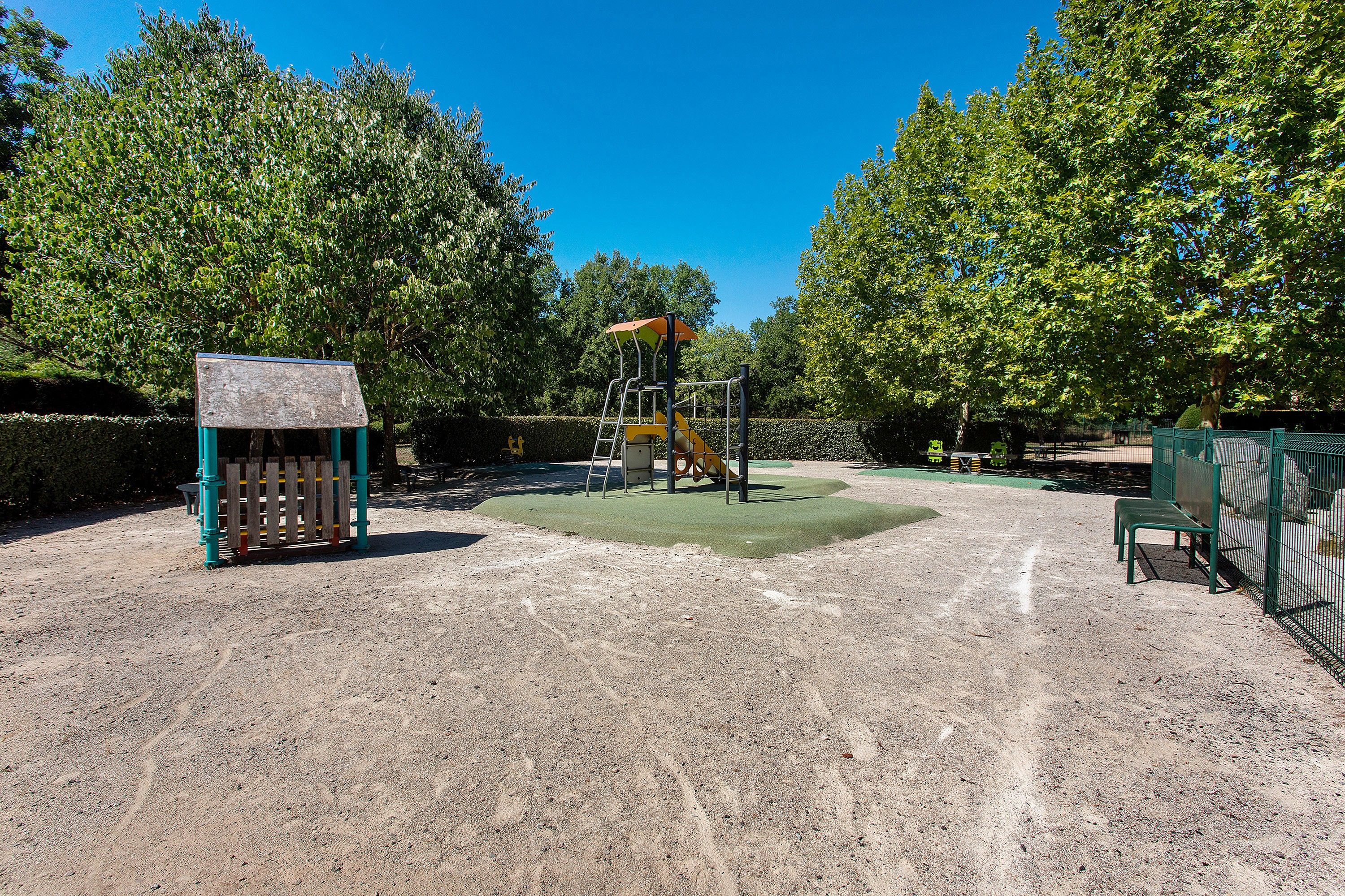 Ein Spielplatz mit Klettergerüst, einer Bank und einem umzäunten Bereich.