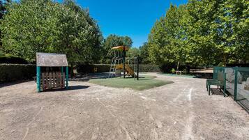 Ein Spielplatz mit Klettergerüst, einer Bank und einem umzäunten Bereich.