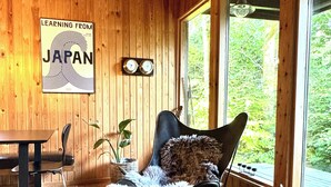 A wooden interior with a dining table, a cushioned chair, a small round table with a candle, and a poster on the wall. - Architectural cottage on 7000 sqm nature plot (Hadsund)