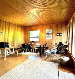 Un interior de madera con zona de comedor, un sofá y un cartel en la pared.