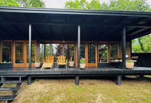 Eine überdachte Terrasse mit Holzstühlen und Blumentöpfen.