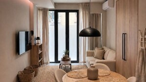 A modern living room with a dining area, a flat-screen TV, and a large window. - Koryfo Old Town Stay by Corfuescapes (Kerkira)