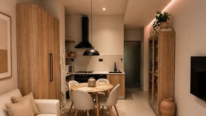 A modern living room with a sofa, dining table, and kitchen area with a TV. - Koryfo Old Town Stay by Corfuescapes (Kerkira)