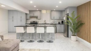 Una cocina moderna con armarios grises, una isla central con taburetes y una planta en maceta.