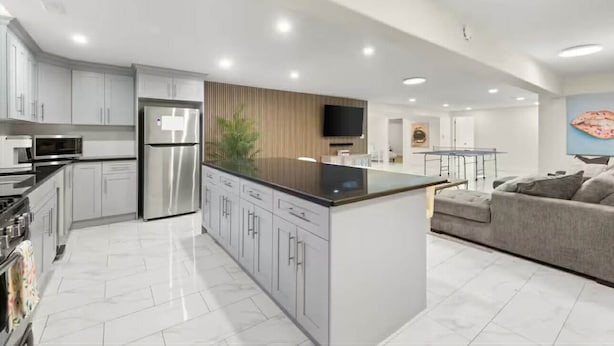 Una cocina moderna con electrodomésticos de acero inoxidable, una isla central y un rincón comedor con sofá.