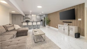 Una sala de estar moderna con un sofá, una mesa de centro y un televisor montado en la pared.