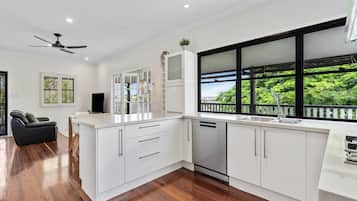 A modern kitchen with white cabinetry, a built-in dishwasher, and a large window with a view of greenery.