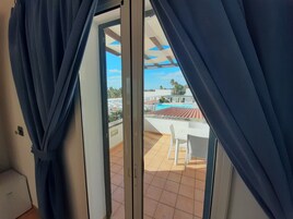 A room with a sliding glass door leading to a balcony with a pool and outdoor furniture.