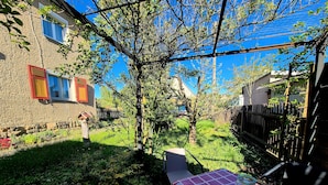 A garden with a table and chairs, a tree, and a building with windows. - Holiday Home 'Elbsandstein vor der Tür' with Private Terrace and Garden (Lohmen)