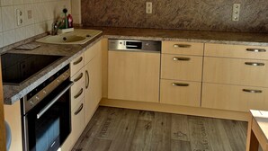 A kitchen with wooden cabinets, a dishwasher, and a stove. - Holiday Home 'Elbsandstein vor der Tür' with Private Terrace and Garden (Lohmen)