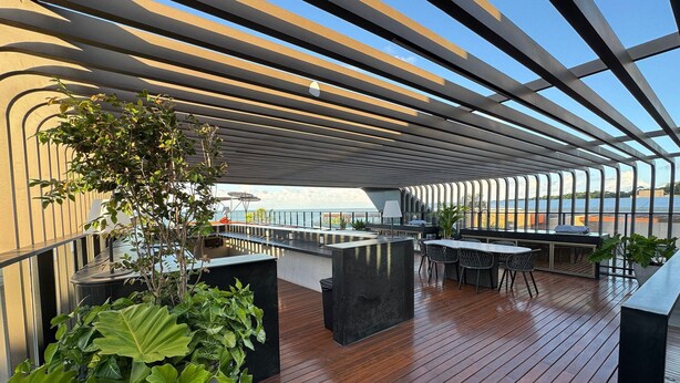 Eine moderne Terrasse im Freien mit Holzboden, Metallgeländern und Blumentöpfen.