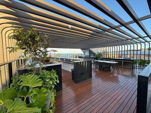 Eine moderne Terrasse im Freien mit Holzboden, Metallgeländern und Blumentöpfen.