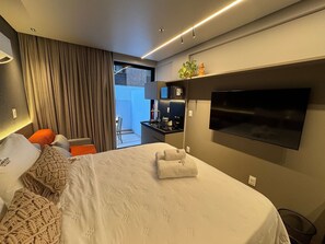 Une chambre d’hôtel moderne dotée d’un grand lit, d’une télévision à écran plat, d’une petite kitchenette et offrant une vue sur l’extérieur.