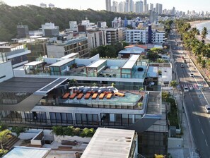 Ein modernes Hotel mit Dachpool und Blick auf Strand und Stadtpanorama.