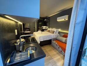 Ein kompaktes Hotelzimmer mit Küchenzeile, einem Bett, einer Couch und einem kleinen Essbereich.