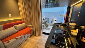 Ein modernes Wohnzimmer mit Sofa, Esstisch und Küchenbereich, inklusive eines Oster Induktionskochfelds.