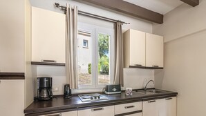 Eine Küche mit Fenster, einer Kaffeemaschine, einem Toaster und Schränken.