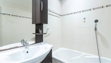 A bathroom with a sink, mirror, dark wooden cabinet, and a shower.